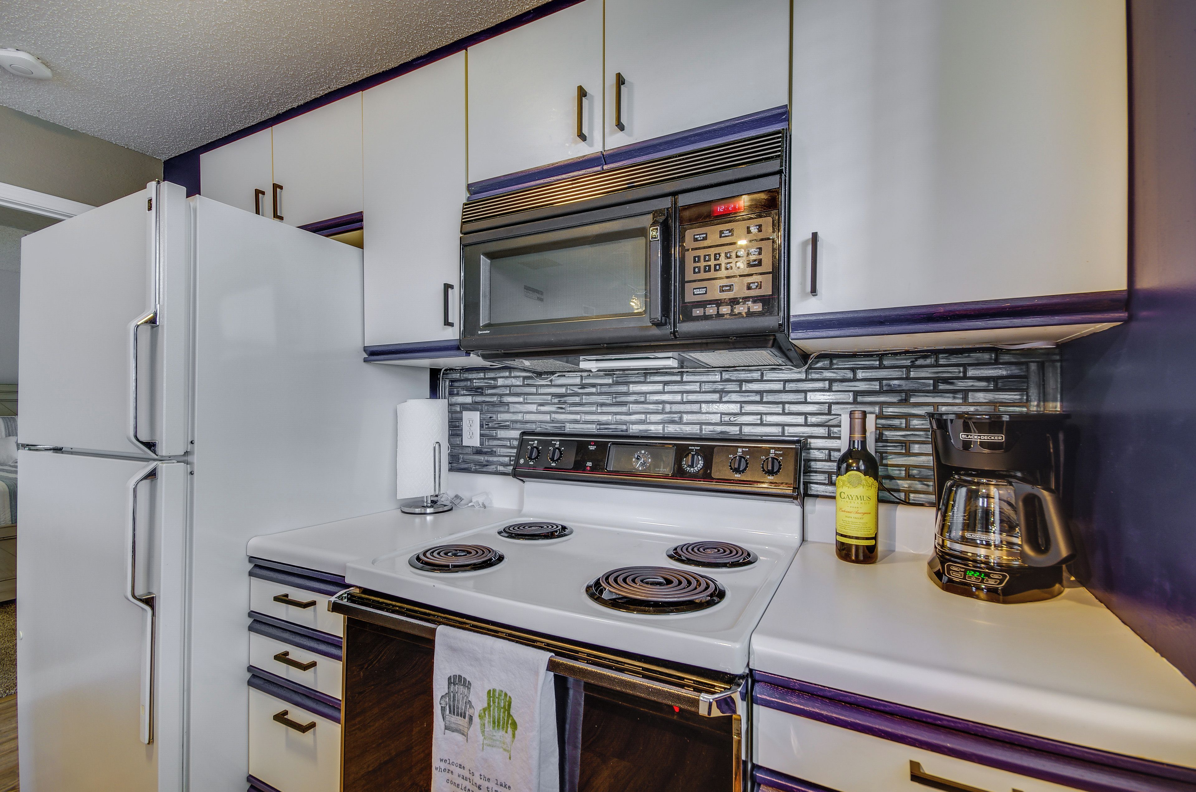 A kitchen with a white refrigerator, a microwave, a stove, and a coffee maker.