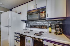 A kitchen with a white refrigerator, a microwave, a stove, and a coffee maker. - Osage Beach Condo w/ Private Deck & Lake Views! (Osage Beach)