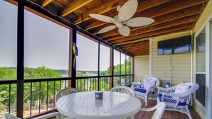 Un espace extérieur abrité, doté d’une table ronde et de chaises, d’un ventilateur de plafond et offrant une vue sur la verdure.