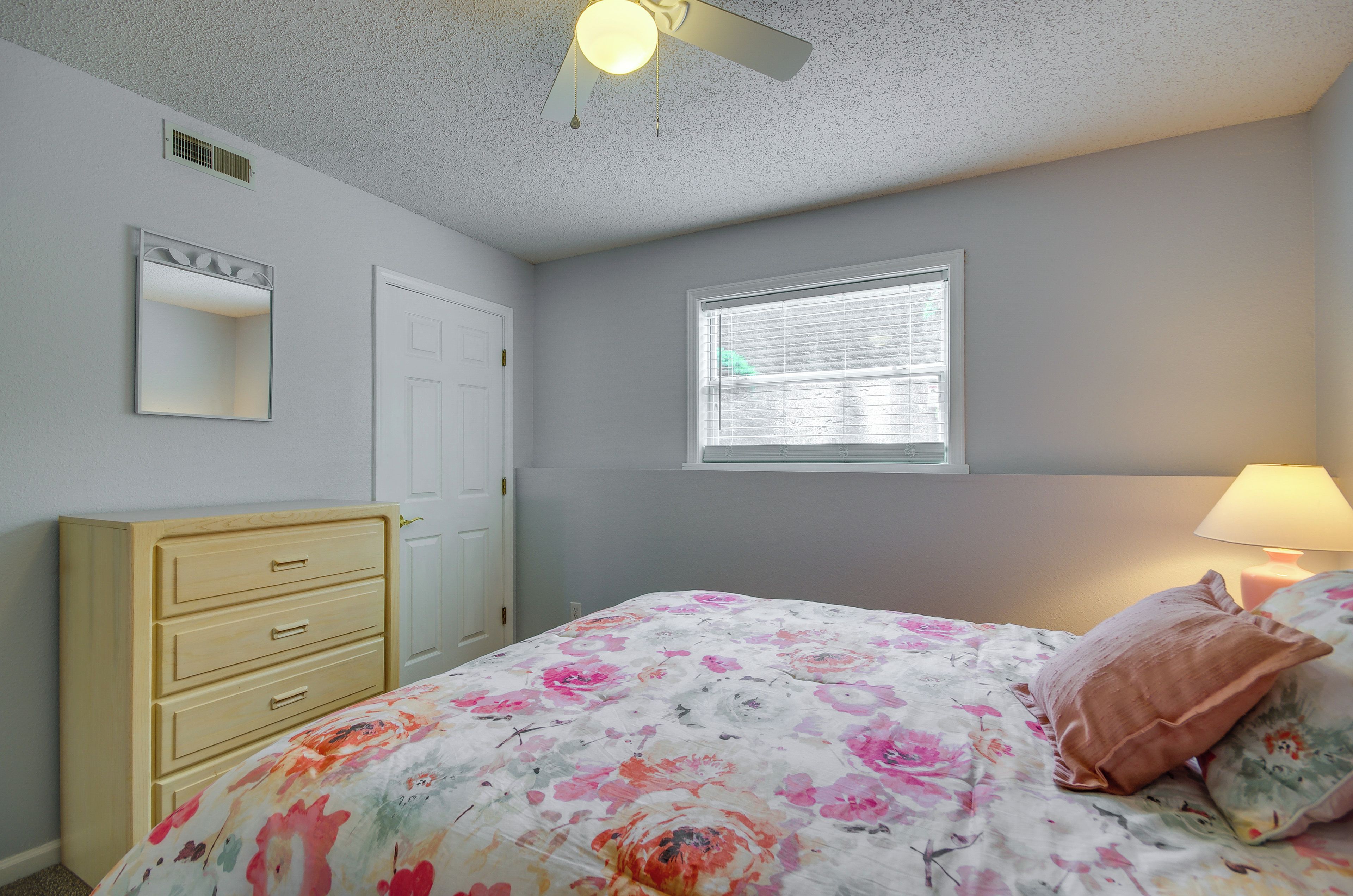 A bedroom with a bed, dresser, window, and ceiling fan.