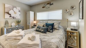 A bedroom with a bed, a dresser, a nightstand, a wall clock, and a window with blinds. - Pool Access & Lake View: Osage Beach Condo! (Osage Beach)