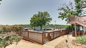 A pool area with a wooden deck, a flag, and a view of hills. - Pool Access & Lake View: Osage Beach Condo! (Osage Beach)