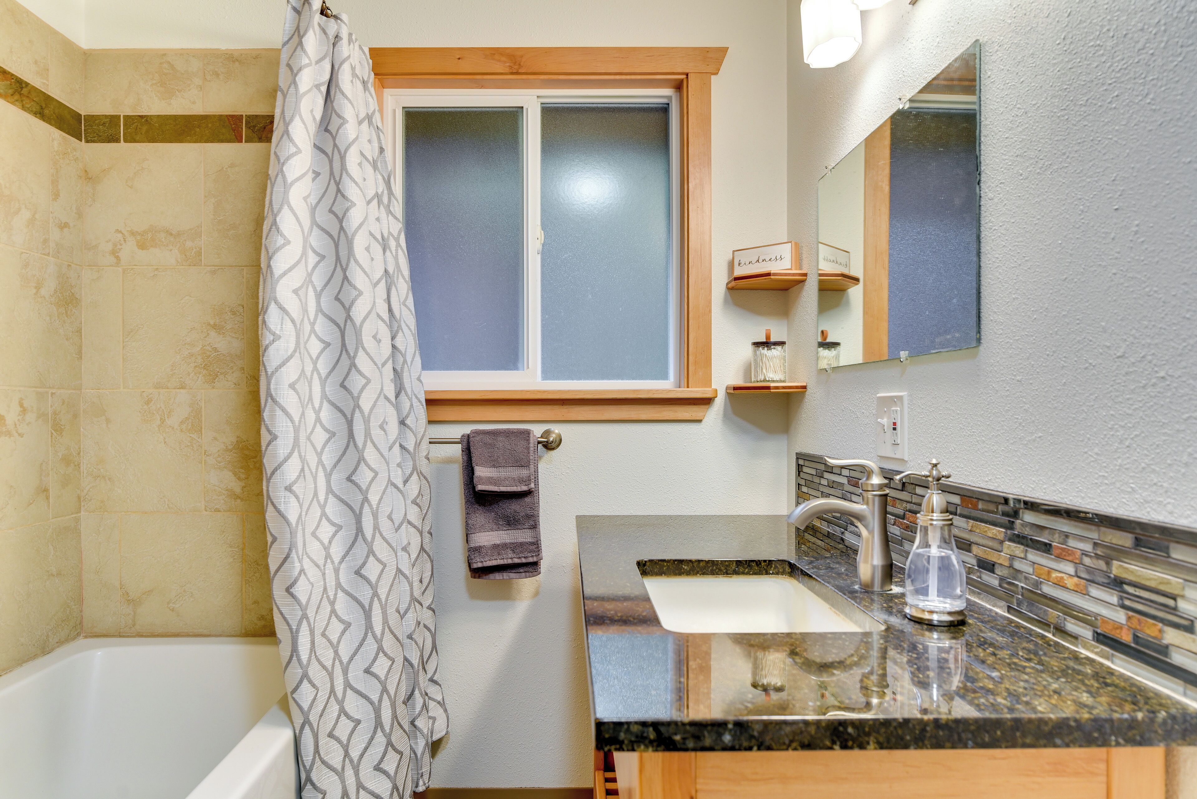 Une salle de bain avec une baignoire, un rideau de douche, une fenêtre, un lavabo et un miroir.