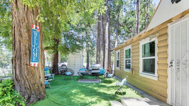 Un jardin avec une pancarte indiquant « BIENVENUE », une table à manger avec des chaises et un patio couvert.