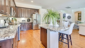 A modern kitchen with dark wooden cabinets, stainless steel appliances, and a marble island. - Retreat w/ Outdoor Oasis! Day Trip to Dtwn Phoenix (Peoria)