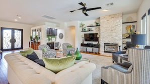 A spacious living room with a large sectional sofa, a fireplace, and a television. - Retreat w/ Outdoor Oasis! Day Trip to Dtwn Phoenix (Peoria)