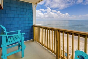 A wooden deck with a blue chair and a wooden bench, overlooking a beach with a clear sky. - North Topsail Beach Vacation Rental w/ Balcony! (Sneads Ferry)