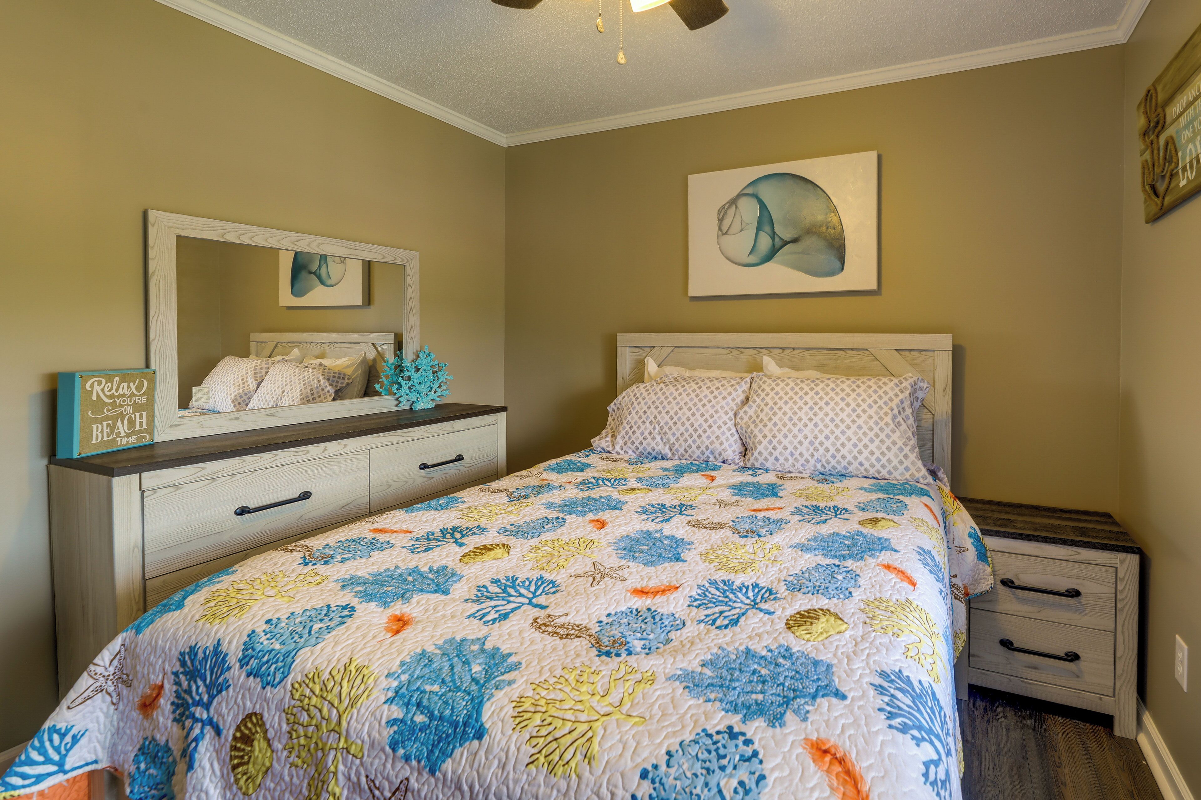A bedroom with a bed, a dresser, a nightstand, a mirror, and a wall with a painting.