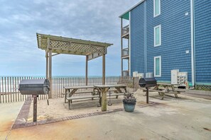 A beachside patio with a wooden pergola, picnic tables, a barbecue grill, and a potted plant. - North Topsail Beach Vacation Rental w/ Balcony! (Sneads Ferry)