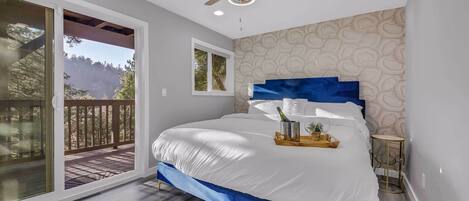 Une chambre avec un grand lit, un ventilateur de plafond et une vue sur un balcon.