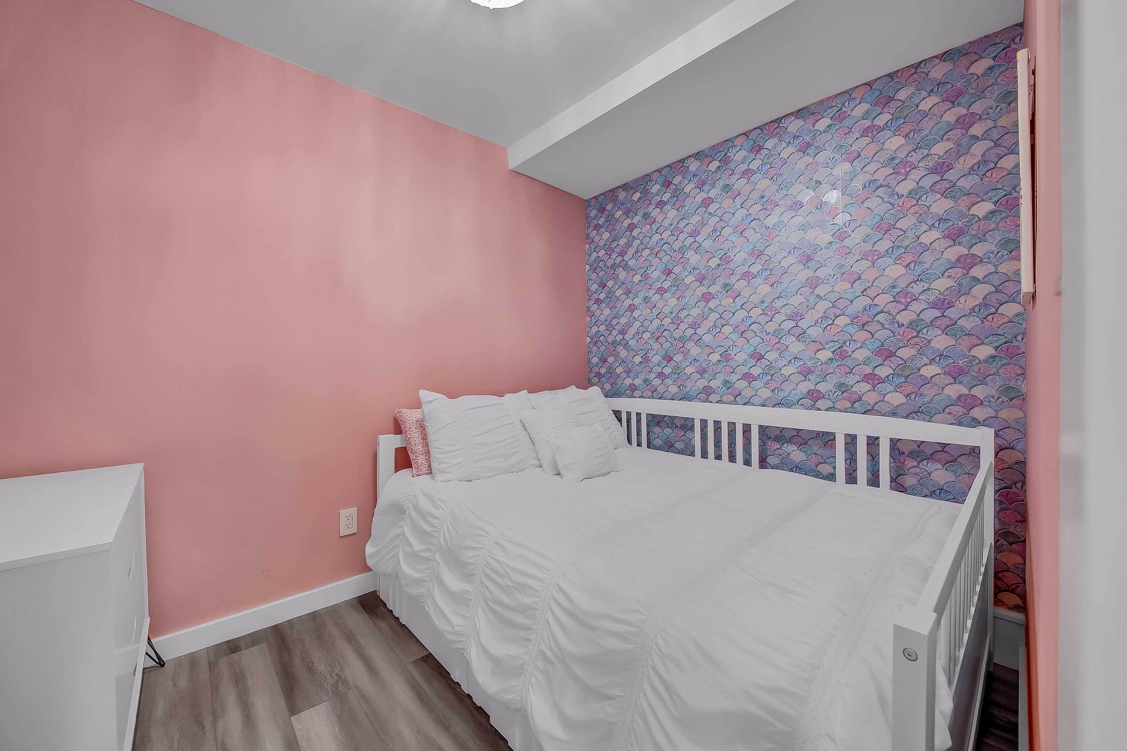 A bedroom with pink walls, a white bed, and a patterned wall.