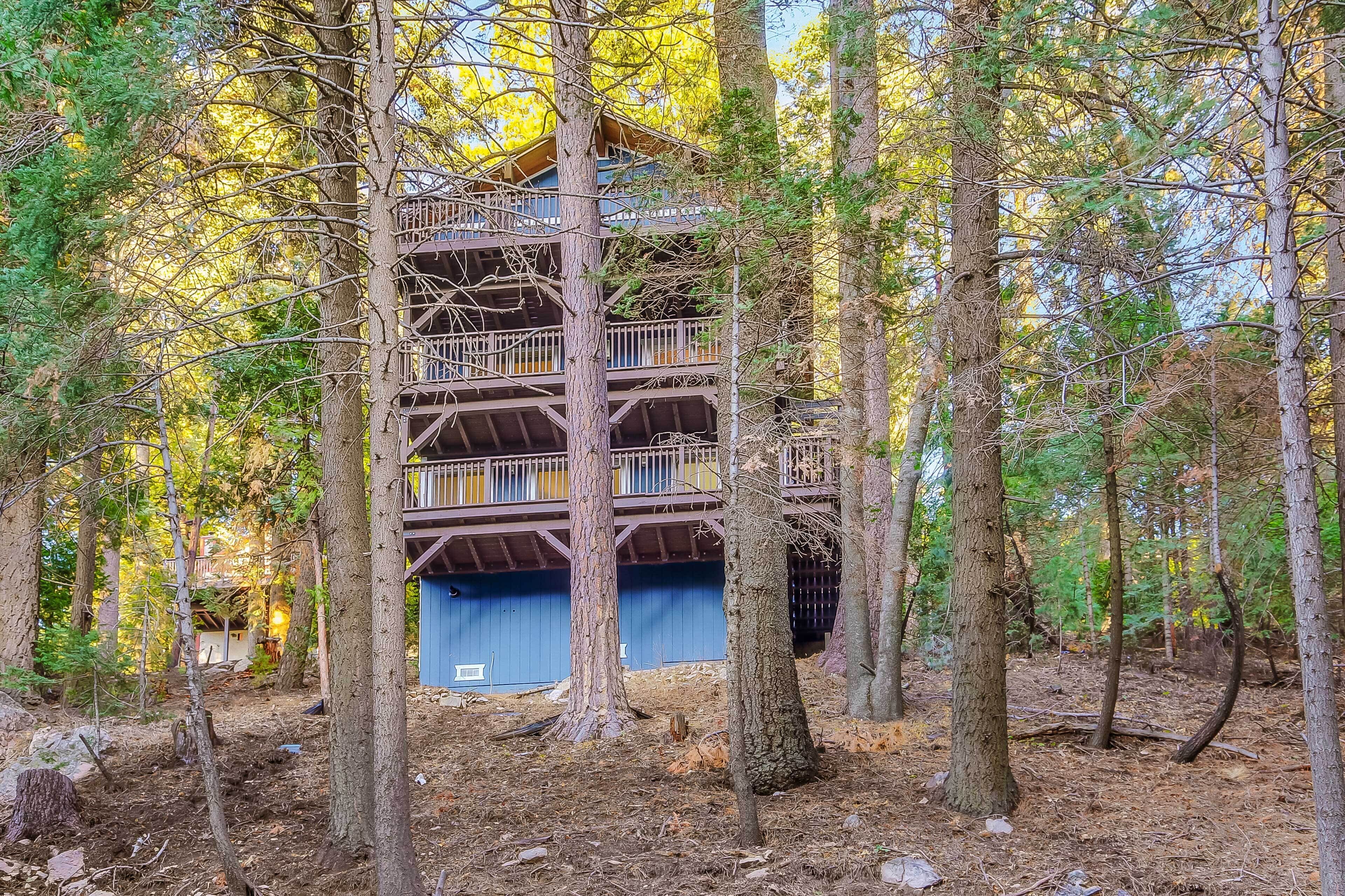 Una cabaña de madera de varios pisos rodeada de árboles en un bosque.