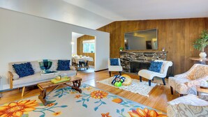 A living room with a sofa, armchairs, a coffee table, and a fireplace. - Expansive Lake Forest Park Home w/ Private Deck! (Lake Forest Park)