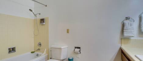 A bathroom with a bathtub, toilet, and towel rack.