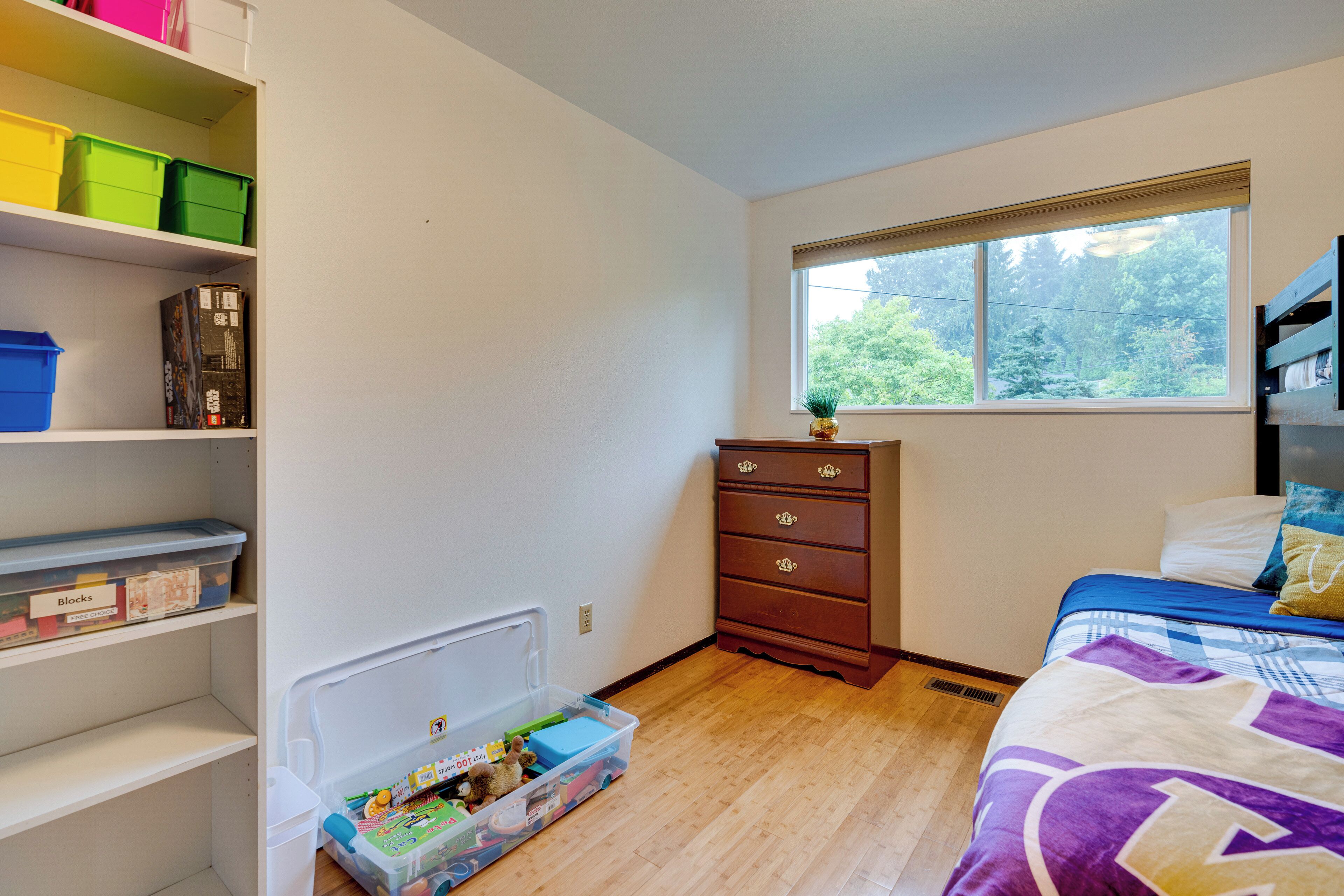 Une chambre à coucher comprenant un lit, une commode, une fenêtre et des meubles de rangement.