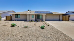 A modern single-story house with a sloped roof, solar panels, and a gravel driveway.
