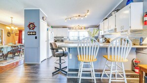 Una cocina moderna con armarios blancos, una barra y un comedor con candelabro.