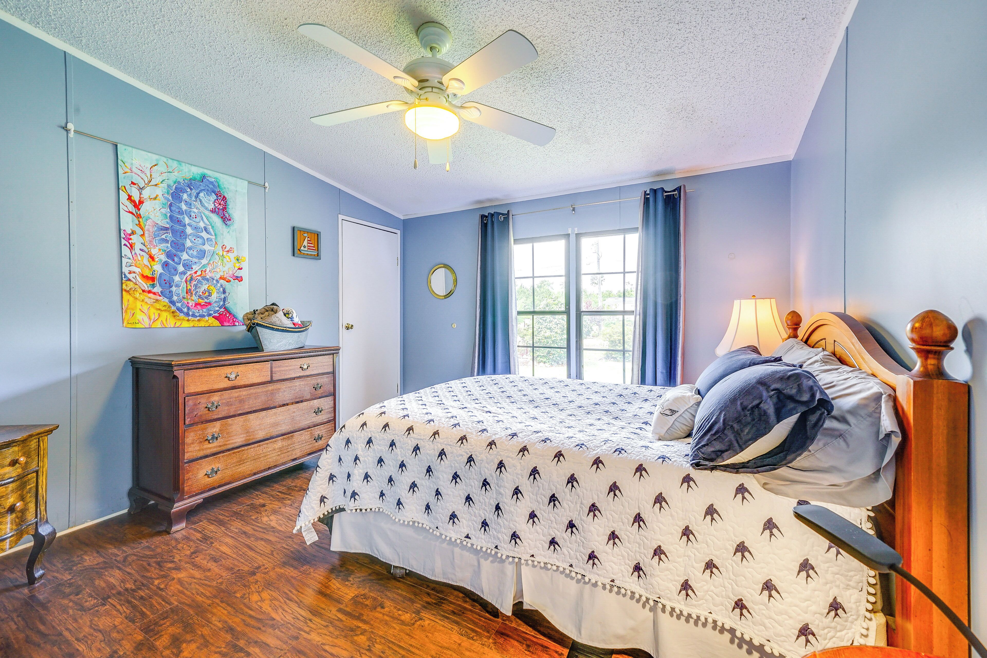 A bedroom with a bed, dresser, and a ceiling fan.