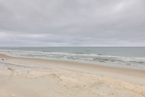 A beach with a sandy shore and calm waves under a cloudy sky. - Oceanfront North Topsail Beach Vacation Rental! (Sneads Ferry)