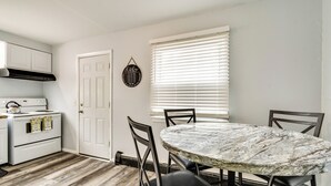 A kitchen with white cabinets, a stove, and a dining table with chairs. - 4 Mi to Dtwn Rochester: Charming Apt w/ Patio! (Rochester)