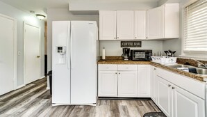 A modern kitchen with white cabinets, a built-in microwave, and a coffee bar sign. - 4 Mi to Dtwn Rochester: Charming Apt w/ Patio! (Rochester)