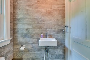 A bathroom with a wooden wall, a white sink, and a toilet. - Charming Buffalo Vacation Rental w/ Covered Patio! (Buffalo)