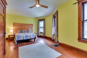 A bedroom with a wooden bed, a ceiling fan, a window with curtains, and a wooden floor. - Charming Buffalo Vacation Rental w/ Covered Patio! (Buffalo)