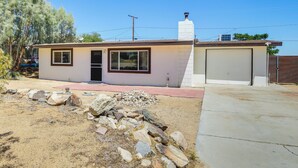 A single-story house with a garage, a small porch area, and a stone pathway leading to the entrance. - Joshua Tree Home w/ Patio - 5 Mi to National Park! (Joshua Tree)