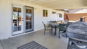 A covered patio with a grill, outdoor seating, and a sliding glass door. - Joshua Tree Home w/ Patio - 5 Mi to National Park! (Joshua Tree)