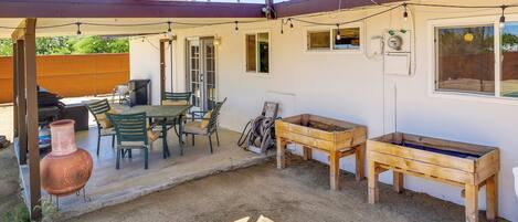 A covered patio area with a table and chairs, a wooden bench, and a large clay pot.