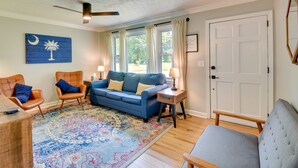 A living room with a blue sofa, two armchairs, a wooden coffee table, a patterned rug, a ceiling fan, and a door with a mirror. - Pet-friendly Greenville Vacation Rental w/ Deck! (Greenville)