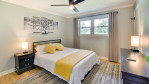 A bedroom with a bed, nightstands, a ceiling fan, a window with curtains, and artwork on the wall. - Pet-friendly Greenville Vacation Rental w/ Deck! (Greenville)