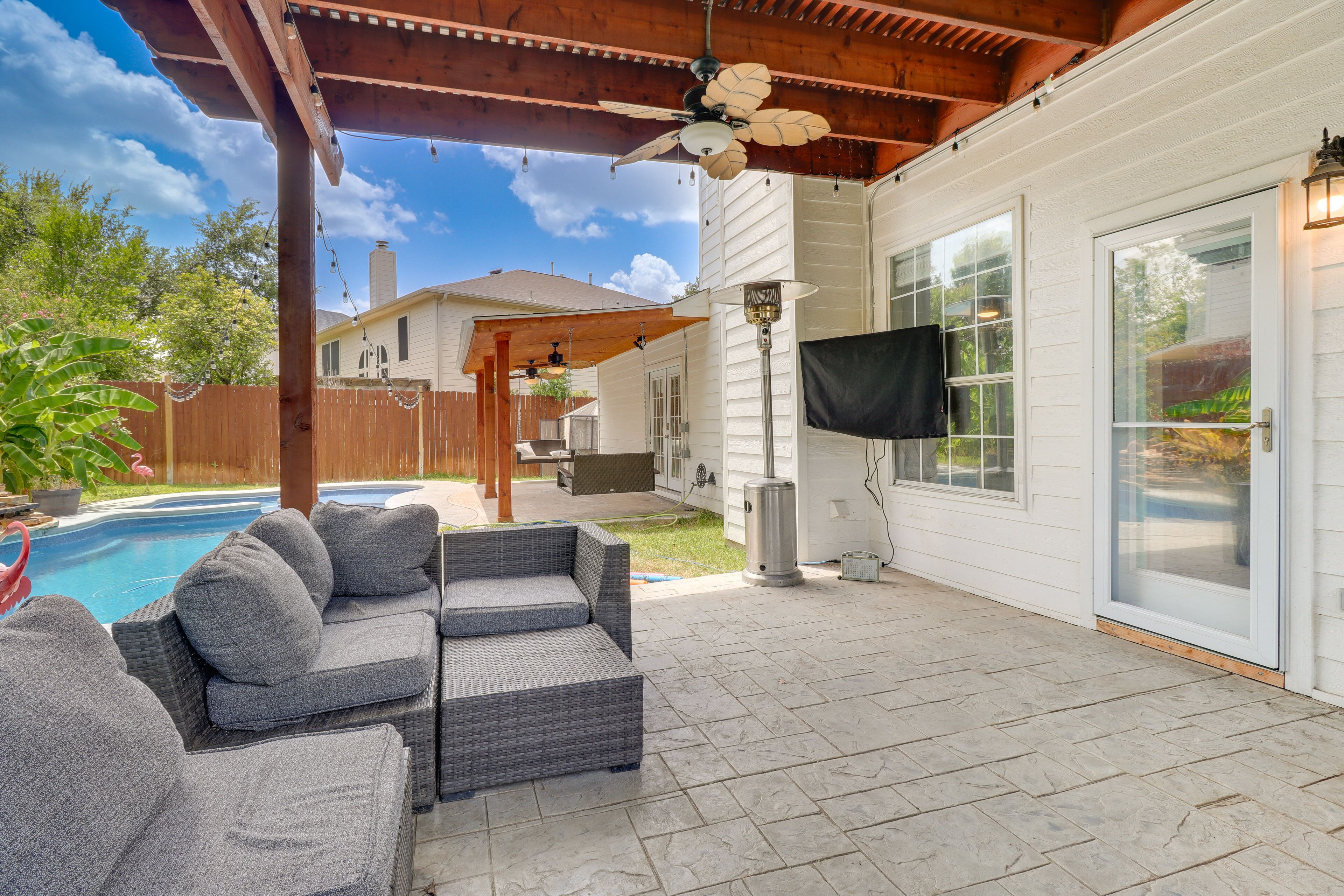 A covered patio with a pool, outdoor furniture, and a ceiling fan.