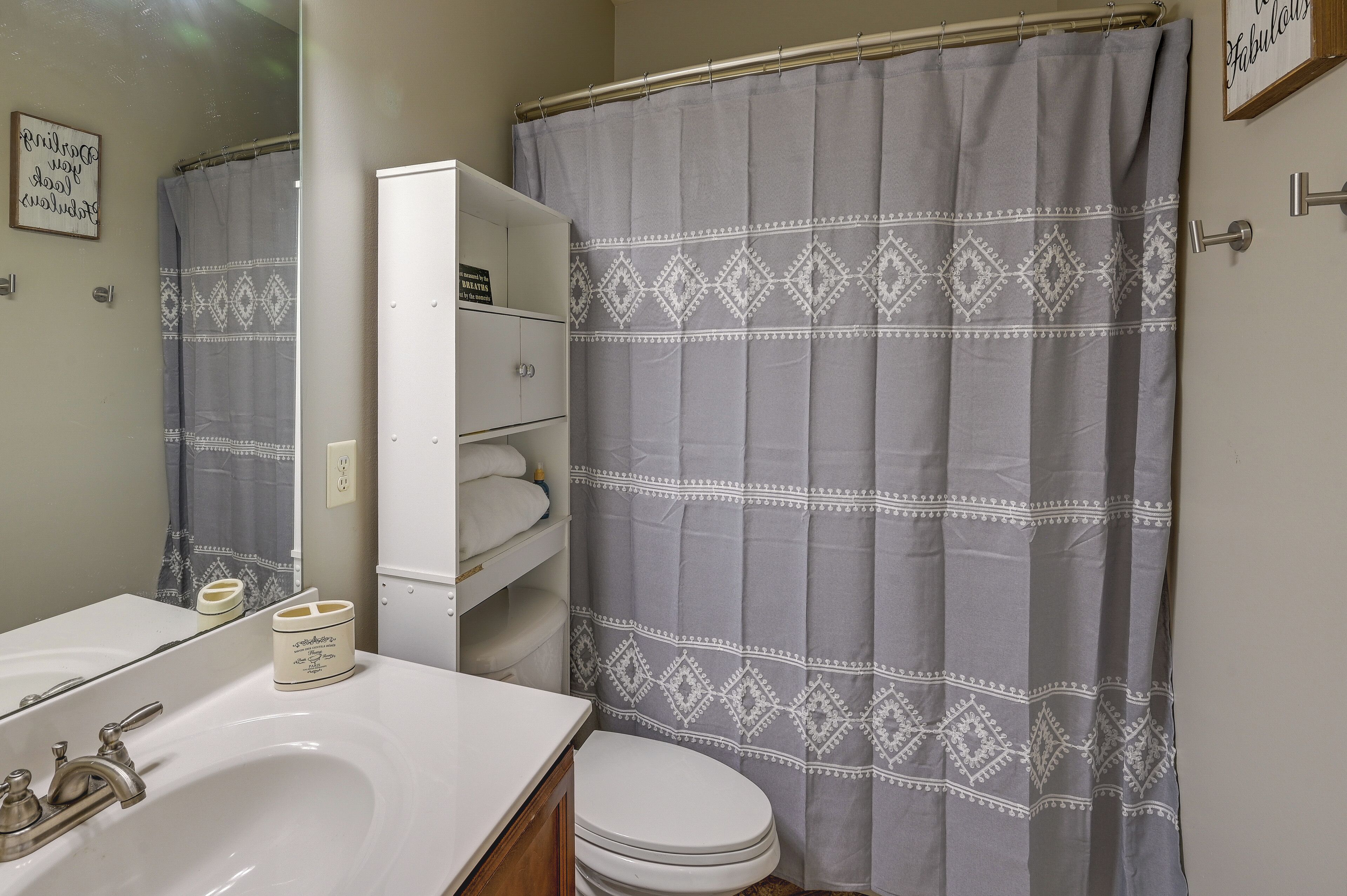 Un baño con lavamanos blanco, inodoro y cortina de ducha con diseño de diamantes.