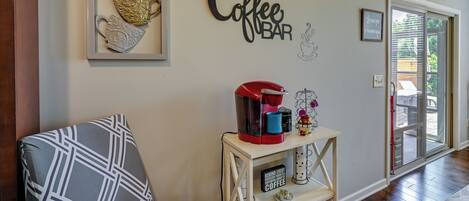 Una sala de estar con una barra para café, un sofá estampado y decoración en la pared.