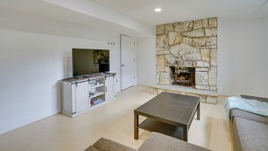 Una sala de estar con chimenea de piedra, televisión, sofá y mesa de centro.