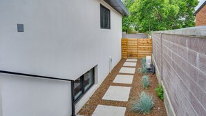 Una casa moderna con un patio estrecho, cerca de madera y un muro de concreto.
