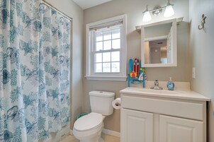 Un baño con inodoro, ventana, lavabo y espejo.