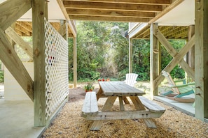 Une pergola en bois avec une table de pique-nique et des bancs, entourée de gravier et de verdure.