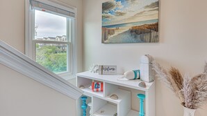 Ein Zimmer mit Blick auf den Strand, ein weißer Konsolentisch mit Dekoration und ein Gemälde mit Strandmotiv.