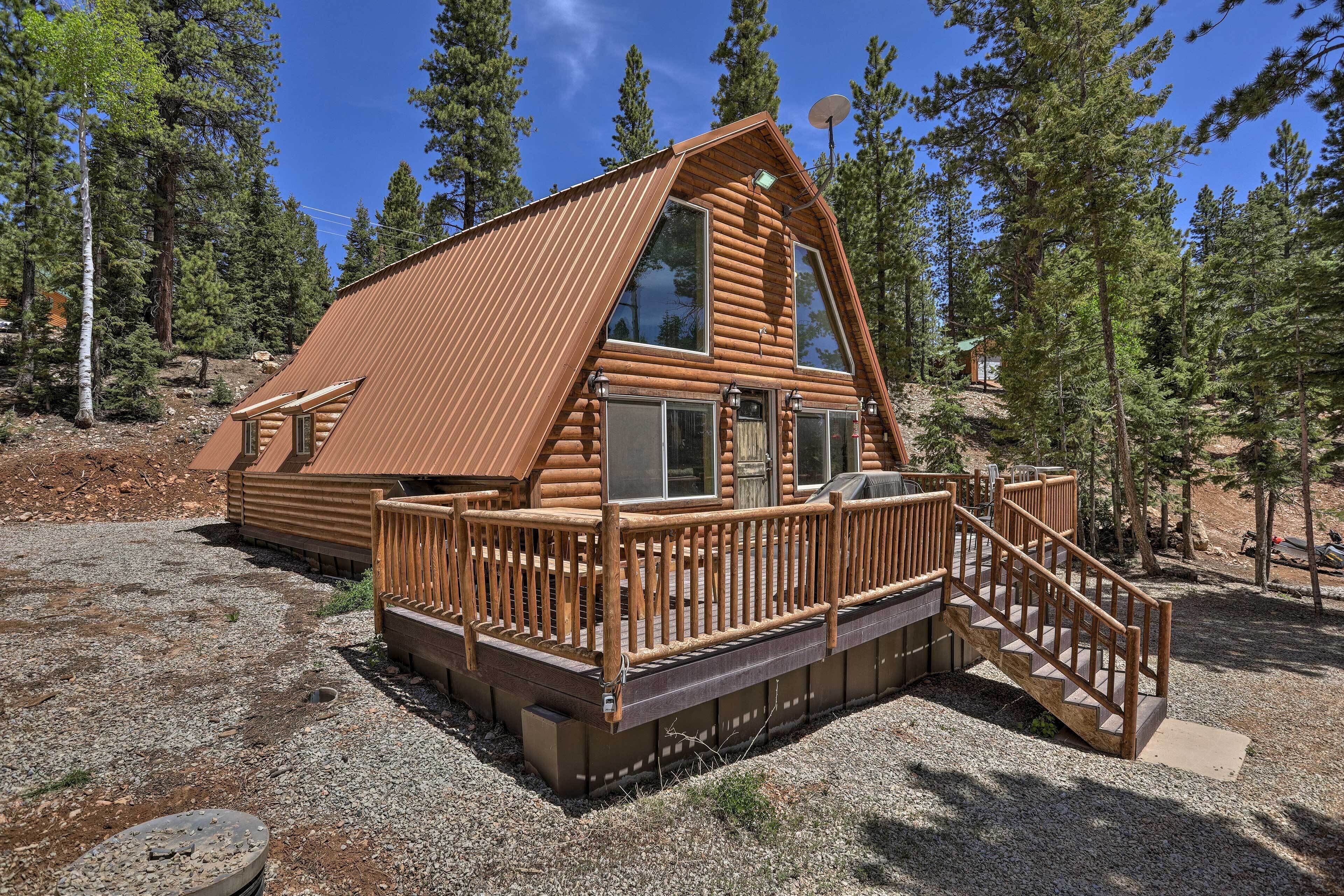 A log cabin with a wooden deck and a staircase leading to the entrance.