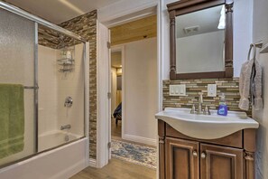 A bathroom with a bathtub, a sink with a mirror, and a shower area. - Cozy Duck Creek Cabin ~ 12 Mi to Nat'l Forest (Duck Creek Village)