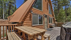 A log cabin with a deck, wooden tables, and a barbecue grill. - Cozy Duck Creek Cabin ~ 12 Mi to Nat'l Forest (Duck Creek Village)