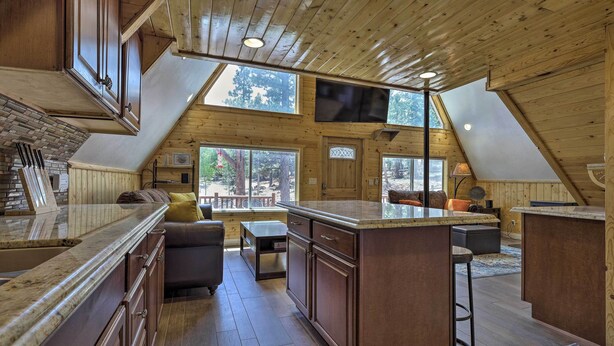 A spacious kitchen with a large island, wooden ceiling, and large windows offering views of the outdoors. - Cozy Duck Creek Cabin ~ 12 Mi to Nat'l Forest (Duck Creek Village)