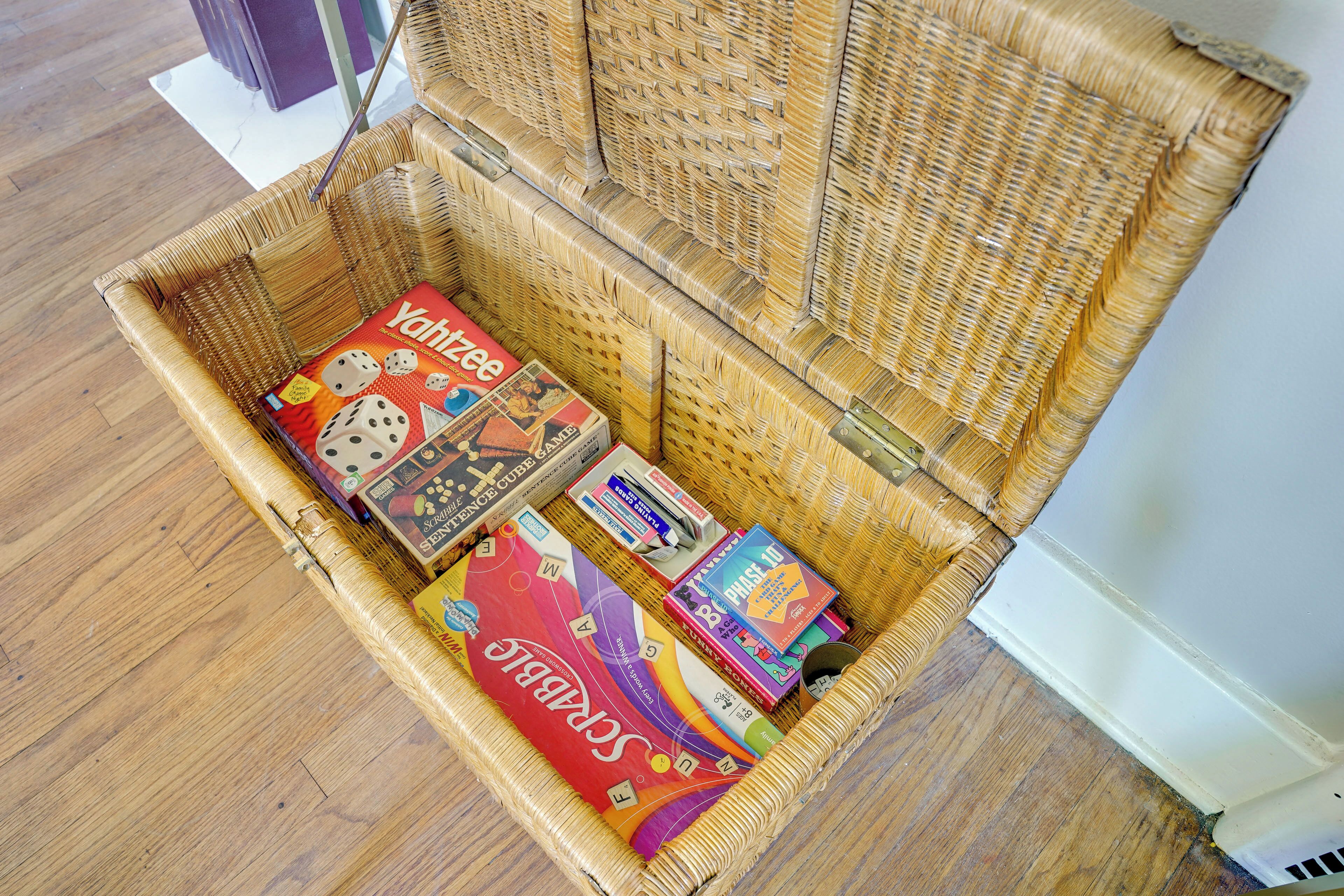 Un panier en osier contenant des jeux de société et un livre.