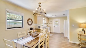 A dining area with a table, chairs, a chandelier, a clock, and a kitchen in the background. - Lake Wales Vacation Rental w/ Direct Canal Access! (Lake Wales)