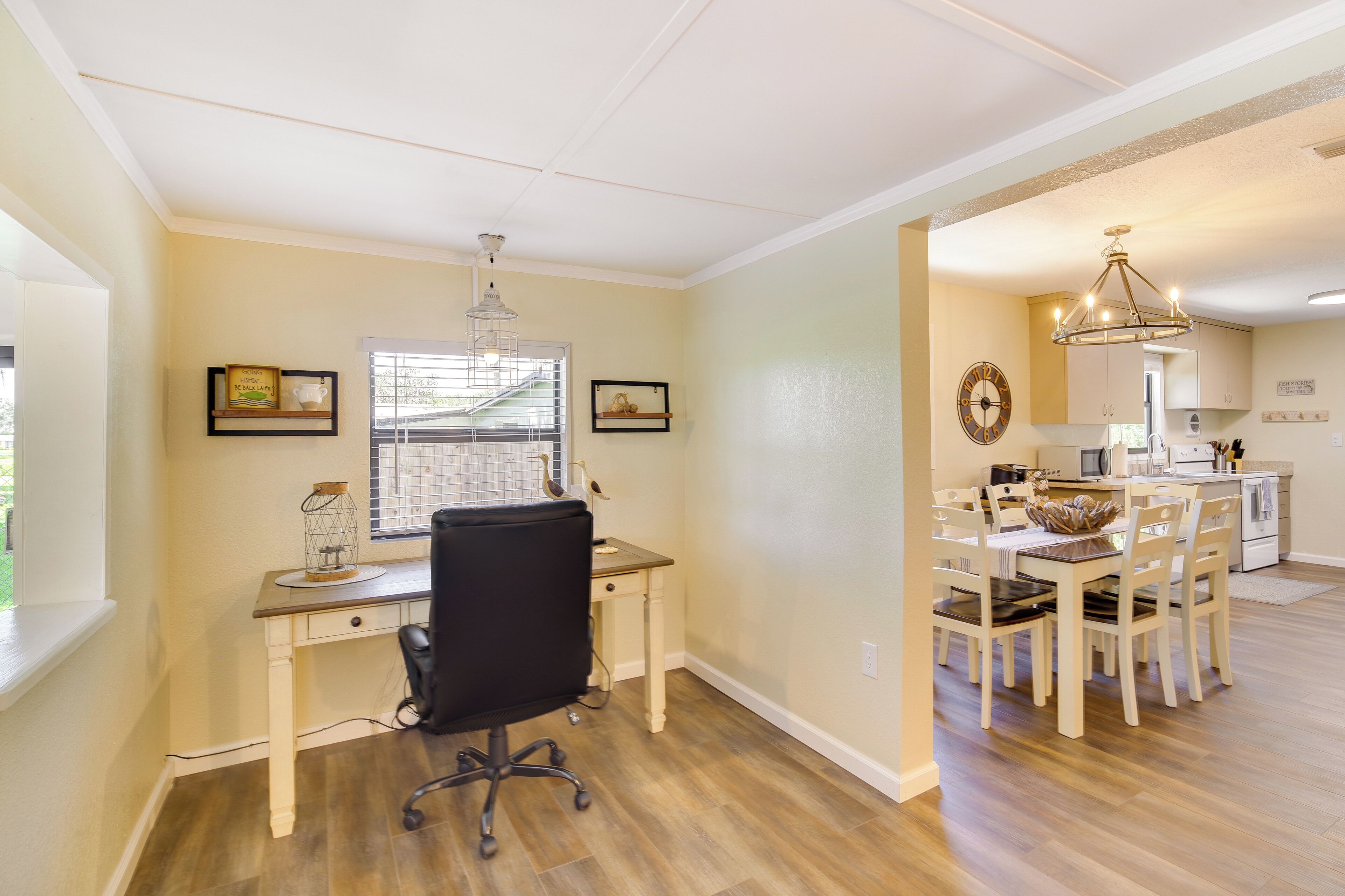 A home office with a desk, chair, and window. There is a dining area with a table and chairs.