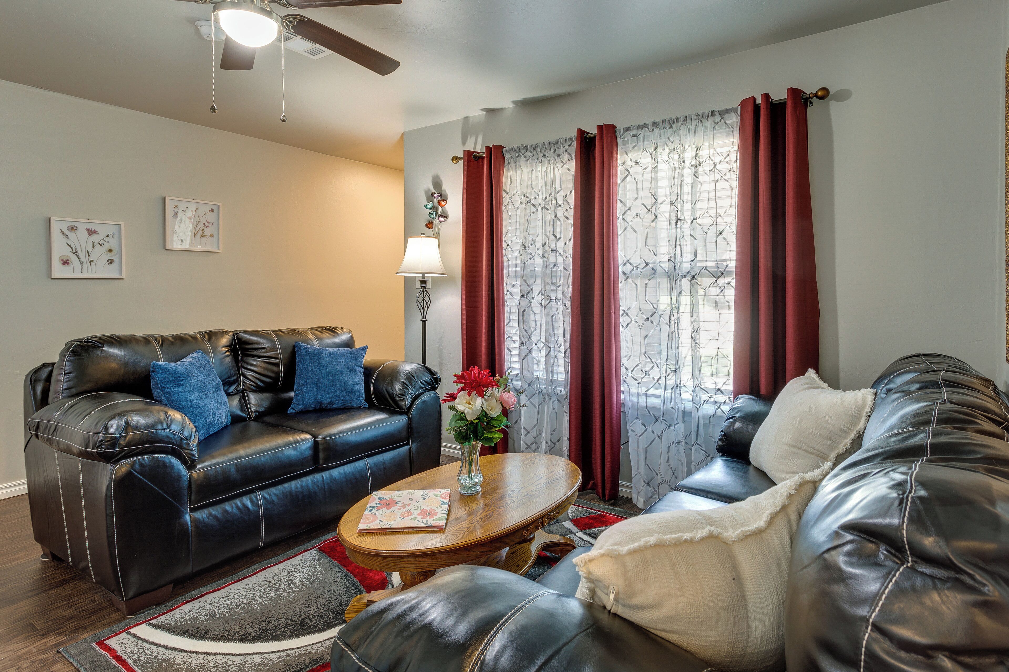A living room with a black leather sofa, a wooden coffee table, and a red curtain.