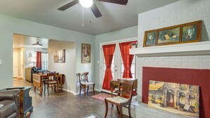 Una sala de estar con chimenea, comedor y un pasillo que conduce a otra habitación.