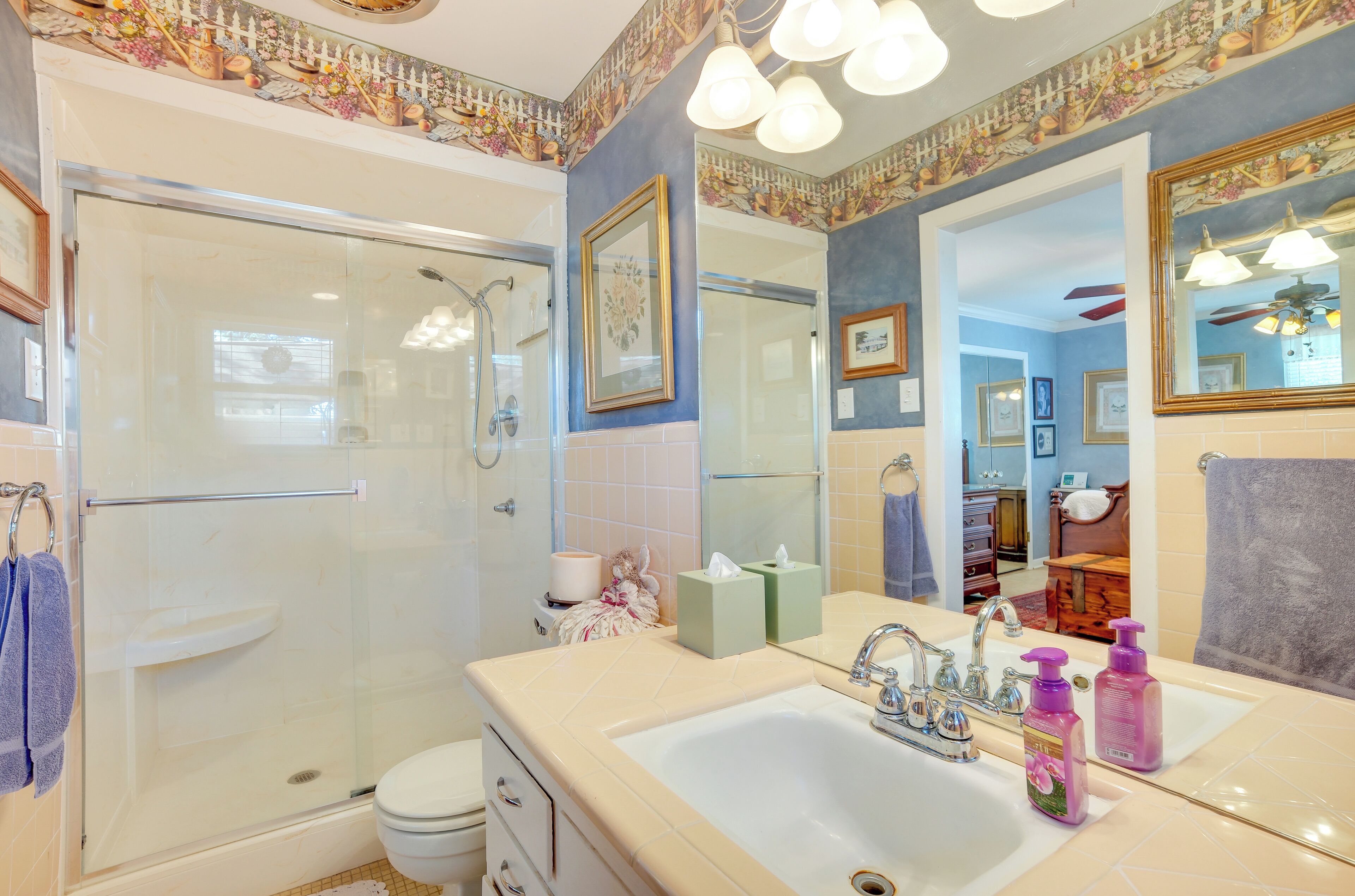 A bathroom with a glass shower enclosure, a sink with a mirror, and a toilet.
